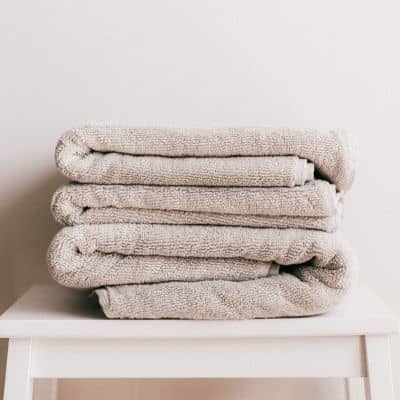 pile de draps de bain éponge écrue sur tabouret blanc
