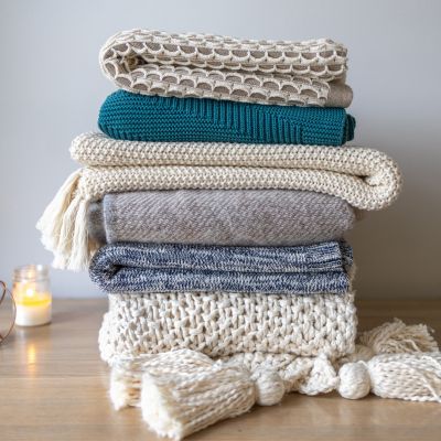 pile de plaids posés à côté d'une bougie